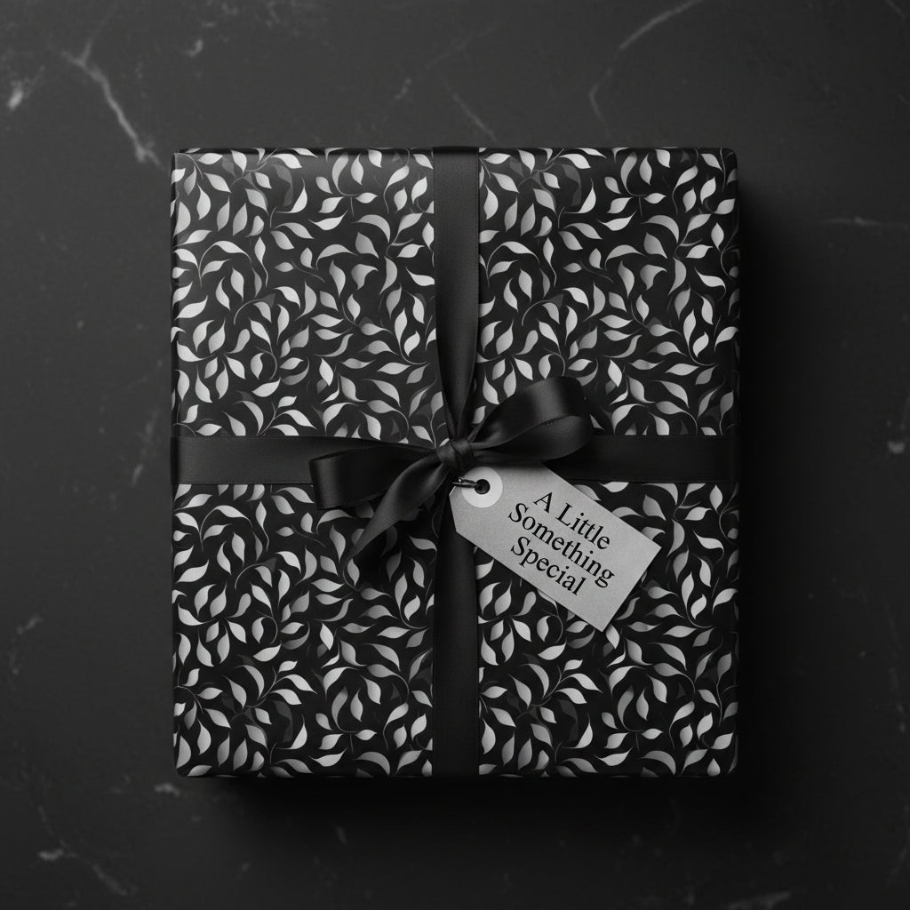 Black and silver floral wrapping paper with satin ribbon and gift tag, perfect for elegant gift-giving.