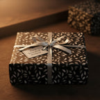 Elegant gift box with black and white leaf pattern wrapping paper, silver ribbon, and "Treasured Moment" tag.