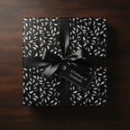 Elegant gift wrapped in black floral wrapping paper with a satin bow, conveying gratitude.