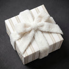 Luxury beige striped wrapping paper by Wrapped Studios on a gift box with a white faux fur bow.