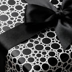 Modern black and white polka dot wrapping paper with a luxury satin ribbon bow by Wrapped Studios.