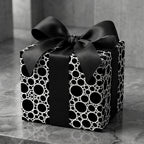 Modern black and white circle pattern luxury wrapping paper with a satin bow by Wrapped Studios.