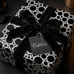 Luxury black and white modern wrapping paper with a velvet bow and Celebrate tag by Wrapped Studios.