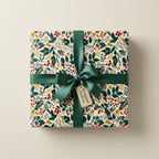 Square gift wrapped in floral Christmas wrapping paper with green satin ribbon and bow.