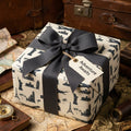 Vintage travel wrapping paper with world landmarks, grey bow, and gift tag by Wrapped Studios.