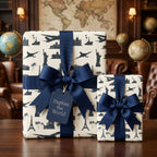 Travel themed wrapping paper with navy blue landmarks and luxury ribbon on gift boxes by Wrapped Studios.