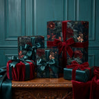 Luxury dark floral wrapping paper with red velvet ribbons on holiday gifts by Wrapped Studios.