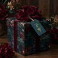Luxury dark floral wrapping paper with a burgundy velvet bow on a gift box by Wrapped Studios.