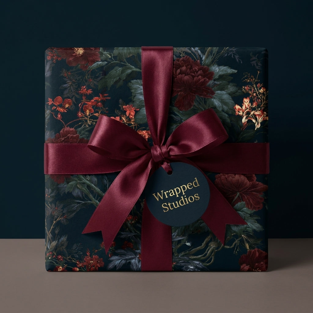 Luxury dark moody floral wrapping paper with a burgundy satin ribbon and tag by Wrapped Studios.