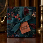 Moody dark floral wrapping paper with a teal ribbon and gift tag. Luxury gift wrap by Wrapped Studios.