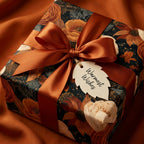 Moody floral wrapping paper with rust satin ribbon and Warmest Wishes gift tag by Wrapped Studios.