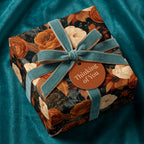 Luxury vintage floral wrapping paper with terracotta flowers and a teal velvet bow, by Wrapped Studios.