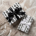 Modern black and white wavy wrapping paper on gift boxes with ribbons by Wrapped Studios.