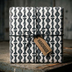 Modern black and white wavy geometric wrapping paper with twine and handmade tag by Wrapped Studios.