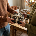Couple exchanging a gift in dark boho floral wrapping paper with cream rope bow, by Wrapped Studios.