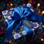 Luxury purple floral wrapping paper on a gift box with a royal blue satin bow by Wrapped Studios.