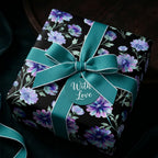 Elegant purple floral wrapping paper with teal bow and tag, luxury birthday gift wrap by Wrapped Studios.