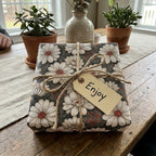 Vintage daisy floral wrapping paper by Wrapped Studios on a rustic gift box with twine and an 'Enjoy' tag.