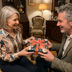 Couple exchanging a gift wrapped in luxury dark floral wrapping paper with a velvet bow by Wrapped Studios.