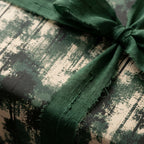 Forest green holiday wrapping paper with frayed ribbon. Rustic luxury gift wrap by Wrapped Studios.