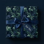 Luxury dark floral wrapping paper with a navy satin ribbon on a gift box, by Wrapped Studios.