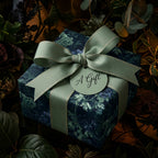 Luxury botanical floral wrapping paper in navy and sage green with ribbon by Wrapped Studios.