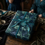 Luxury dark teal floral wrapping paper with a velvet bow on a gift box by Wrapped Studios.