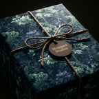 Luxury dark floral wrapping paper in moody green and blue with a rustic twine bow, by Wrapped Studios.