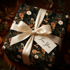 Dark vintage floral wrapping paper on a gift box with a cream satin bow, by Wrapped Studios.
