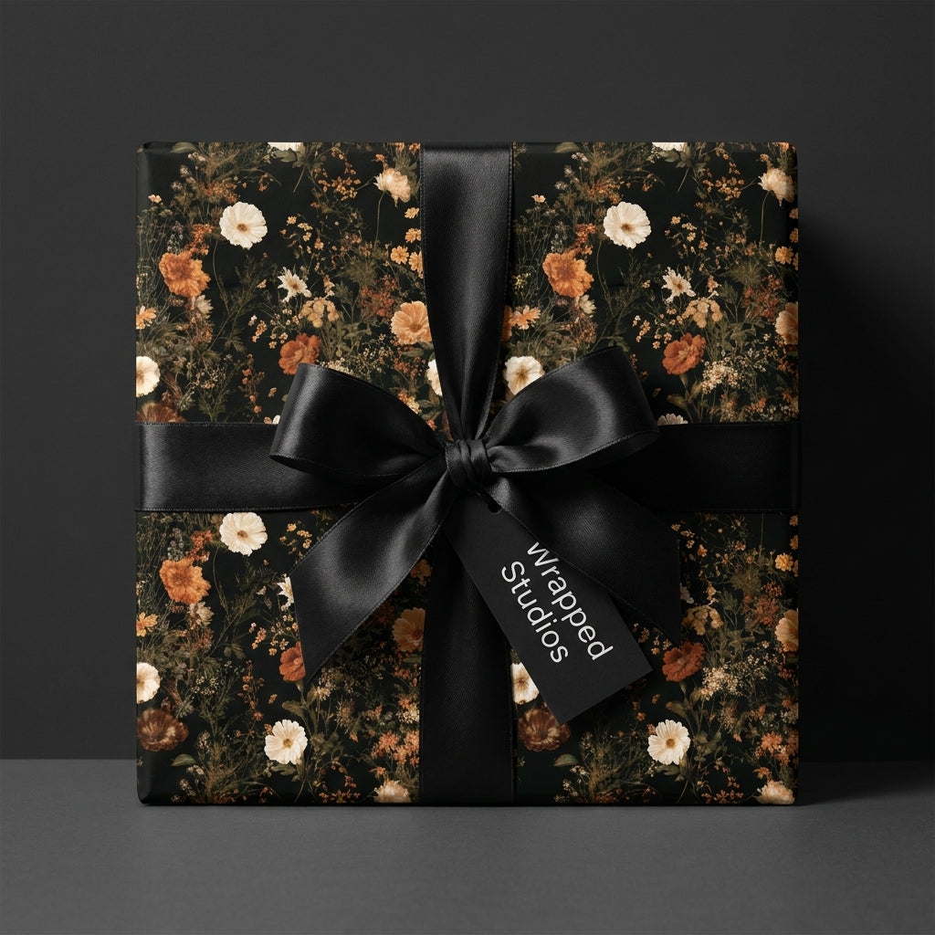 Dark moody floral wrapping paper with a black satin bow on a gift box by Wrapped Studios.
