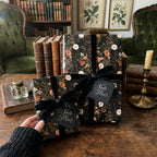Dark floral wrapping paper with black velvet ribbons on gifts in a vintage library by Wrapped Studios.