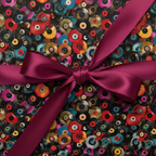 Gift box wrapped in colorful vinyl record pattern wrapping paper and tied with a magenta satin bow.