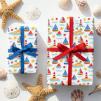 Nautical wrapping paper with sailboats and lighthouses on gifts with red and blue bows by Wrapped Studios.