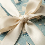 Nautical wrapping paper with a sailboat pattern and a cream-colored satin ribbon.