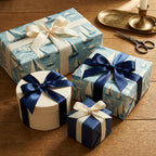 Elegant gifts wrapped in sailboat-patterned paper with navy and cream ribbons on a wooden table.