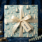 Square gift wrapped in sailboat patterned paper with cream ribbon; nautical gift wrap.