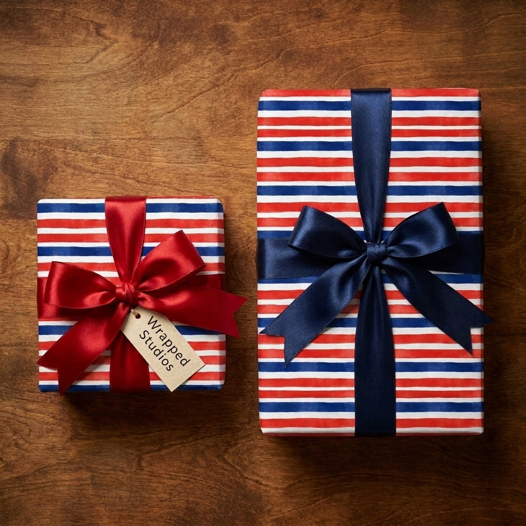 Patriotic red white and blue striped wrapping paper with satin bows on wood background by Wrapped Studios.