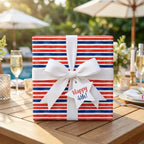 Red, white, and blue striped 4th of July wrapping paper with a white bow by Wrapped Studios.