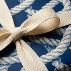 Nautical rope wrapping paper in navy blue with a cream textured ribbon bow by Wrapped Studios.