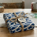 Nautical wrapping paper in navy blue rope pattern by Wrapped Studios, tied with rustic twine on a wooden table.