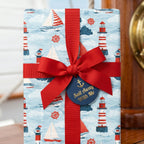 Nautical wrapping paper with sailboats and lighthouses, tied with a red bow by Wrapped Studios.
