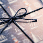 Nautical sailboat wrapping paper tied with a dark twine bow, elegant gift wrap by Wrapped Studios.