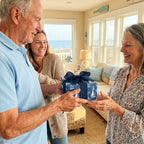 Blue nautical wrapping paper with sailboats on a gift held by a family. Wrapped Studios.