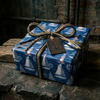Nautical wrapping paper with sailboats and lighthouses, tied with a rustic twine bow by Wrapped Studios.