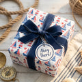 Coastal nautical wrapping paper with sailboats, lighthouses, and a navy bow by Wrapped Studios.