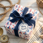 Coastal nautical wrapping paper with sailboats, lighthouses, and a navy bow by Wrapped Studios.
