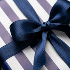 Navy blue and white striped wrapping paper with a luxury satin bow by Wrapped Studios.