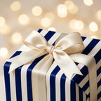 Luxury navy blue striped wrapping paper with an ivory bow and festive lights by Wrapped Studios.