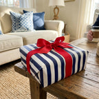 Navy blue striped wrapping paper with a red bow on a coffee table by Wrapped Studios.