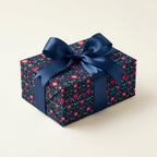 Gift box wrapped with floral gift wrap pattern and blue ribbon on a light beige background